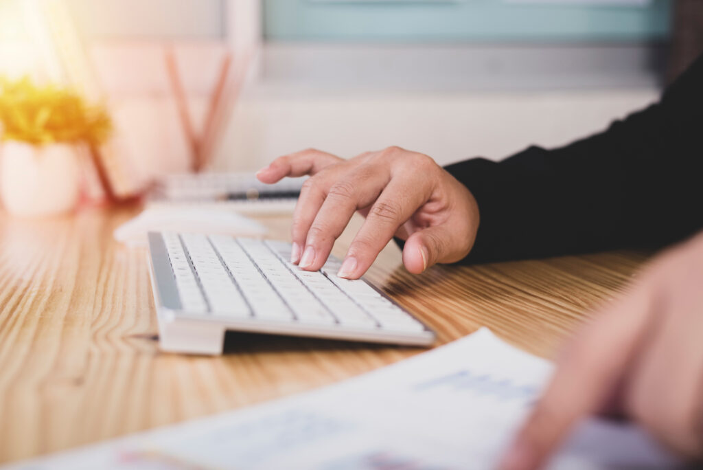 main droite sur un clavier et main gauche avec le doigt qui pointe une ligne d'un document